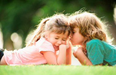 Çocuk ve kız bahar bahçesinde birbirlerine sevgiyle sarılıyorlar. Parkta sarılan iki küçük çocuk. Çocuklar dışarıda beraber oynuyorlar. Çocuklar Gras 'da öpüşüp sevişiyor.