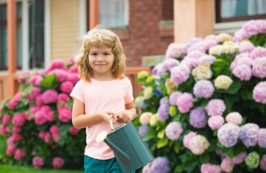 Çocuk, anne babaya su bidonuyla yardım ediyor. Bahçe malzemeleri