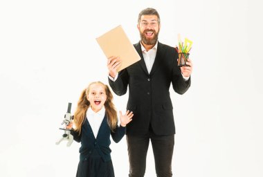 Stüdyoda heyecanlı öğretmeni olan ilkokul öğrencisi, izole edilmiş. Kitabı olan öğretmen ve okul malzemesi olan kız öğrenci beyaz arka planda izole edilmiş.