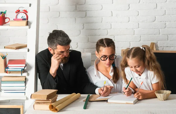 父は女子学生を教えている 学校の教室で父と子供の娘 読書と執筆 — ストック写真