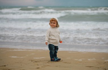 Sonbahar denizindeki küçük çocuğun portresi. Sahilde soğuk havada çocuklar kavramı