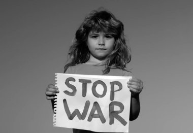 Çocuk savaşı protesto ediyor. Portreci çocuk savaşı durdurun diyor, yazıyla bayrağı kaldırıyor savaşı durdurun. Kelimelerle tabelayı tutan çocuk dışarıda duran savaşı durdurun.