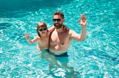 Baba oğul havuzda yüzüyor, yaz ailesi. Havuz partisi. Babası yüzme havuzunda oynayan bir çocuk. Yaz tatili. Aquapark. Baba oğul boş vakit.