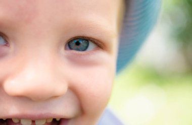 Bahar çocukları portresi. Mavi gözlü sevimli, gülümseyen çocuğun yakın yüzü. Çocuk duyguları konsepti. Dışarıdaki gülen çocuğun portresi.