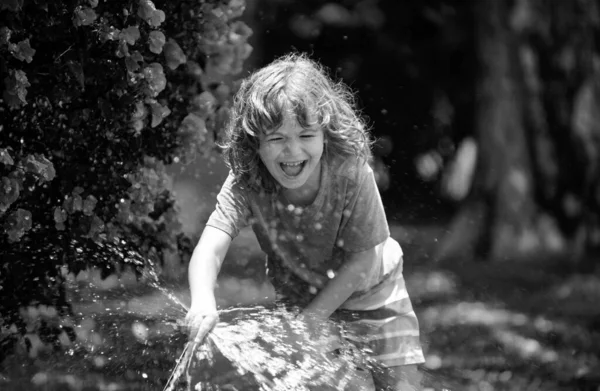 Kid have fun. Funny boy happy smiling on natural landscape. Little child have fun on fresh air. Being funny is one of my greatest strengths. Watering plants in the garden at home on summer sunny day