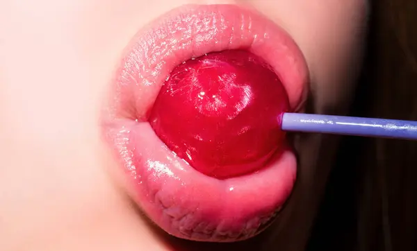 Licking candy. Lollipop model. Woman lips sucking a candy. Glamor sensual model with red lips eat sweats lolly pop