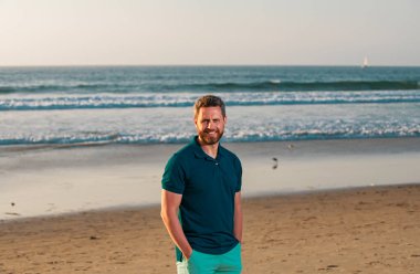 Sahildeki bir adamın portresi. Güneşli bir günde, açık havada mutlu bir genç adam