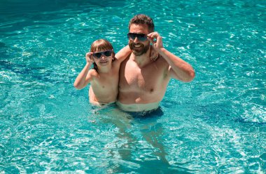 Baba oğul havuzda yüzüyor, yaz ailesi. Havuz partisi. Aile eğlencesi. Yaz tatili. Baba ve oğul havuzda.