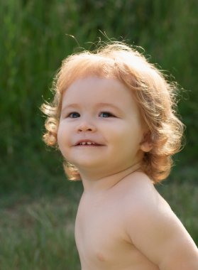 Çocuk portresi, doğa parkındaki sevimli çocuğun başını yakın çekim. Bebek gülümsüyor, sevimli gülüyor