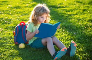 Çim arka planıyla ilgili güzel bir çocuk kitabı. Çocuklar parkta kitap okuyor. Öğrenme kavramı