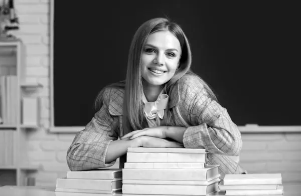 Portrait of smiling young college student in classroom. happy attractive young woman student with books on blackboard