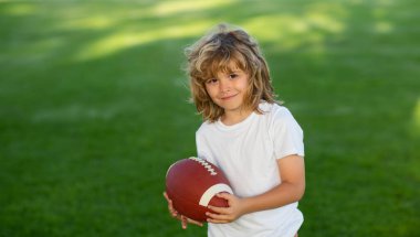 Amerikan tarzı futbol. Amerikan futbolu ya da parkta rugby oynayan Amerikalı bir çocuk. Sportif çocuklar. Futbolcu topu tutuyor