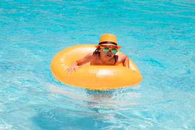 Çocuk 7, 8, 9 yaşlarında yüzme havuzunda yüzüyor. Çocuklar yazlık komik surat