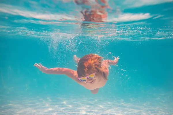 Kid boy swim underwater in summer pool. Summer kids vacation concept. Funny kids face underwater. Child splashing in swimming pool. Summer water sport. Summer vacation with child