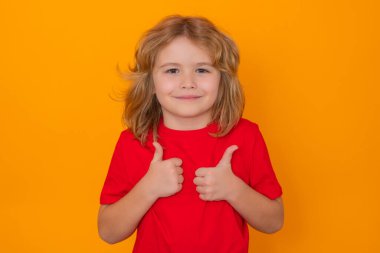 Child showing thumbs up on studio isolated background. Portrait of kid boy making thumbs up sign. Happy kid, happy and smiling emotions