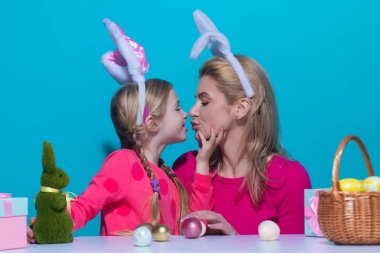 Bir anne ve kızı Paskalya yumurtası boyuyor. Mutlu aile Paskalya için hazırlanıyor. Anne ve kızı yumurta boyuyor. Anne ve çocuk paskalya tavşanı kulağı takıyor.