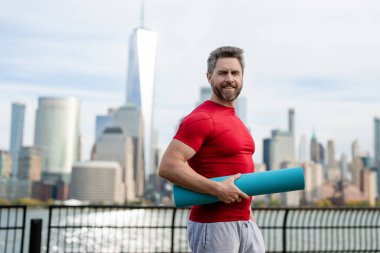 Spor salonundaki son sınıf öğrencisi Manhattan yakınlarında egzersiz yapıyor. Sağlıklı bir emeklilik hayatı. Aktif kıdemli adam dışarıda egzersiz yapıyor. Emeklilikten sonra aktif. Olgun emekli sporcu esneme egzersizleri yapıyor.