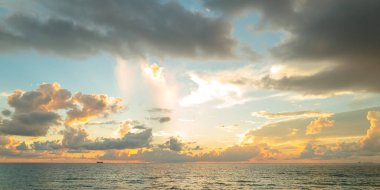 Gündoğumu denizi. Bulutların arasından gün batımını izleyen sakin bir deniz. Meditasyon okyanusu ve gökyüzü arka planı. Huzurlu deniz manzarası. Günbatımı deniz suyunun üzerinde bir ufuk. Gün batımı gökyüzü sakin