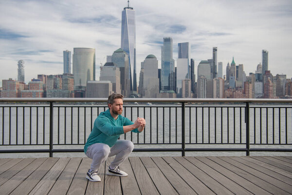 Man squats outdoor. Sports fit man doing Fitness in NYC. Fitness Man. Athlete doing workout practice Fitness for cardio. Fitness workout outdoor. Man outdoor workout. Man enjoying sport in NYC