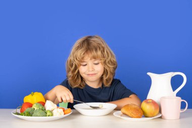 Çorba içen çocuk. Çocuklar kahvaltı yapar. Tatlı çocuk öğle yemeği çorbası içiyor. Çocuğun organik gıda, yoğurt ve süt yiyişinin yakından görüntüsü. Çocuklar sağlıklı beslenir. Gülümseyen küçük çocuk mutfakta yemek yiyor.