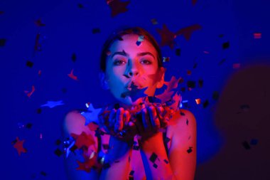 Doğum günün kutlu olsun. Konfeti üfleyen kızın stüdyo portresi. Doğum günü ya da sevgililer günü için konfeti. Seksi model doğum gününde konfeti üflüyor. Doğum günü esprilerini kutlayan şehvetli kadın.