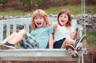 Cute excited amazed little children playing outdoors. Portrait of two happy young kids at the spring park. Cute lovely boy and girl in backyard. Sister and brother walking in garden