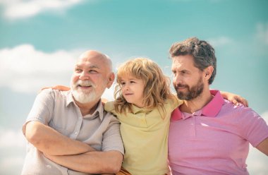 Üç nesildir birlikte, gülümseyen çocuk, baba ve büyükbaba portresi. Büyükbaba ve oğul çocuk portresi. Babalar Günü. Farklı yaşlardaki erkekler.