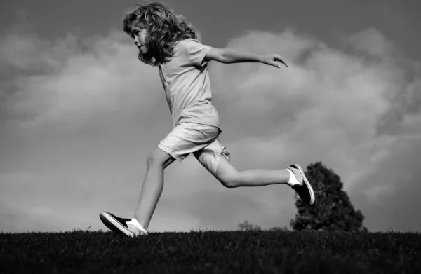 Child fun run outdoors. Kid playing in summer park. Little boy running on green fresh grass field