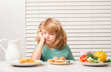 Portrait of kid with no appetite. Concept of loss of appetite. Child eats organic food. Healthy vegetables with vitamins. Proper kids nutrition concept