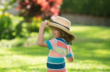 Yazlık doğa parkında saman şapkalı küçük sarışın bir çocuğun portresi. Komik yaz çocuğu suratı. Yaz tatili