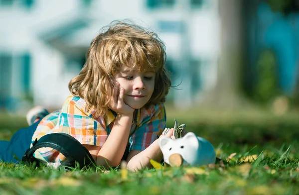 Dzieciak Oszczędza Zakup Trzyma Różową Świnkę Leży Trawie Uczenie Się — Zdjęcie stockowe