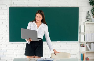 Odaklanmış öğrenci, genç bir kadın internette dizüstü bilgisayarda webinar izliyor, eğitim kurslarını dinliyor, sınıfta çalışma masasında çalışıyor, para kazanıyor. Bilgisayar teknolojisi olan kız öğrenci, uzaktan öğrenim