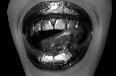 Dudaklarında altın boya var. Altın dudaklar, şehvetli kadın ağzı. Metalik yaratıcı sanat yakın plan. Altın kavram. Seksi dilli. Şehvetli yalama