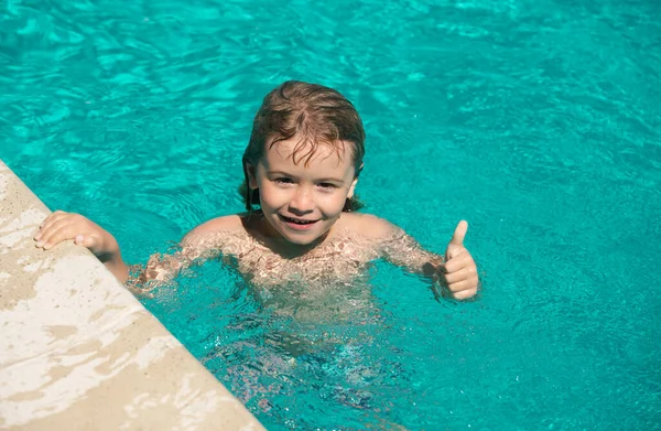 Parmağını kaldırmış çocuk yüzme havuzunda yüzüyor