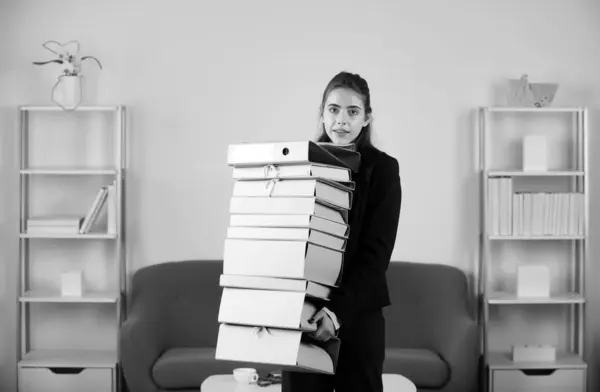 Overworked in the office. Female worker exhausted with too much paper work, documents. Young business woman freelancer or ceo employee working in office
