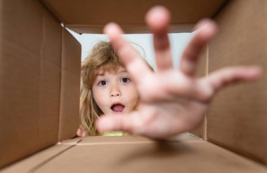 Çocuk bir karton kutuyu açıyor ve içine bakıyor, hediyeyi elle alıyor. Kutuları açmak, sürpriz boks yapmak. Paketler ve teslimat