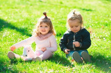 Yaz tarlasında tatlı bir oğlan ve kız. Mutlu çocuklar bahar parkında yeşil çimlerde oturuyor.