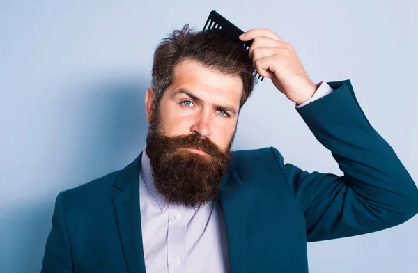 Man hairstyle, modern haircut. Man styling his hair with a comb. Bearded man with beard, bearded gay. Barbershop concept. Mustache men