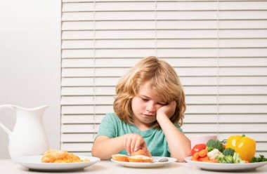 İştahsız bir çocuğun portresi. İştah kaybı kavramı. Çocuk organik yiyecekler yiyor. Vitaminli sağlıklı sebzeler. Gerçek çocuk beslenme konsepti