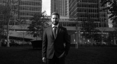 Yönetici işadamı. Modern ofis yakınlarında takım elbiseli bir CEO portresi. Şirket binasının önünde duran mutlu lider.