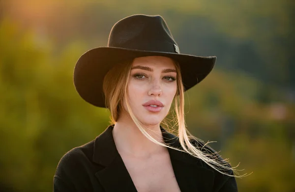 Portrait of a young woman in elegant hat with a wide brim, close up face of beautiful woman outdoor. Cheerful female model. Trendy autumn hat