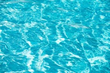 Yüzme havuzundaki mavi suyun arka planında güneş yansıması, havuzda dalgalı su dalgaları. Temiz su arkaplanı