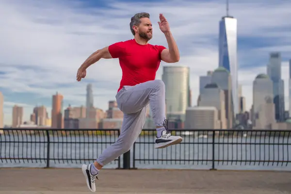 ランナーマン 健康的なスポーツ ニューヨーク市で走る男 フィットネスマンランナーはマンハッタンの近くでジョギングをしている アメリカン ストリートで走る男 スポーツ服でニューヨークで走る男 ランナー用スポーツウェア — ストック写真