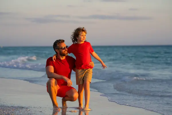 Dad and son boy hugging on beach. Summer holiday. Dad and son enjoying summer vacation together. Daddy and son playing on beach. Friendly family. Dad and child spending time at sea. Fathers day