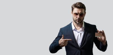 Gri arka planda plastik kredi kartı gösteren bir iş adamı portresi. Slogan ya da metin için boş alan. İş ve başarı kavramı. Başlık için afiş, kopyalama alanı. Web tasarımı için poster