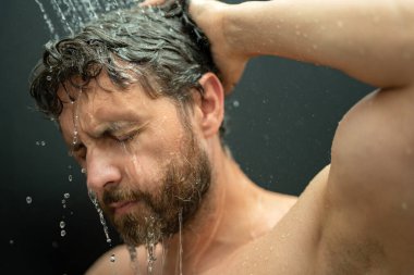 Saç yıkayan bir adam, yakın plan bir portre. Banyoda duş alırken saçlarını yıkarken. Erkek model duşta saç yıkıyor. Adam duş alıyor. Duş alan adam, saç bakımı. Erkek şampuanı ve saç yıkama konsepti