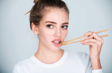 Yemek çubukları seksi dudakların yanında. Yemek çubuklarıyla dudak karıştıran güzel bir kız. Sushi reklamı için seksi bir ağız. Çin yemeği mi Japon yemeği mi?