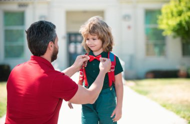 Akıllı çocuk. Sevimli okul ineği. Entelektüel çocuk papyon takıyor. Okul konseptine geri dönelim. Akıllı küçük çocuk çalışmaya hazır. Baba oğluna okula kadar eşlik ediyor.