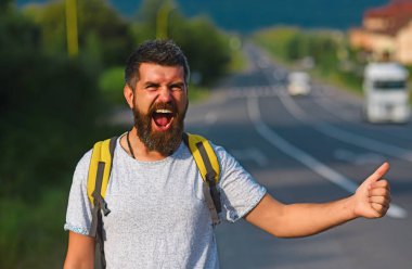 Otomatik durdurma. Hippi arabayı durdurup, jesti bozmaya çalışıyor. Neşeli yüzlü ve sakallı bir adam arka planda otostop çekerek seyahat ediyor. Seyahat ve otostop konsepti