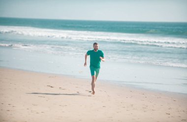 Man running on beach. Jogging on a sandy beach near sea or ocean